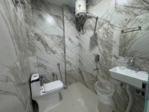 Une salle de bain avec des murs en marbre, des toilettes, un lavabo et une douche.