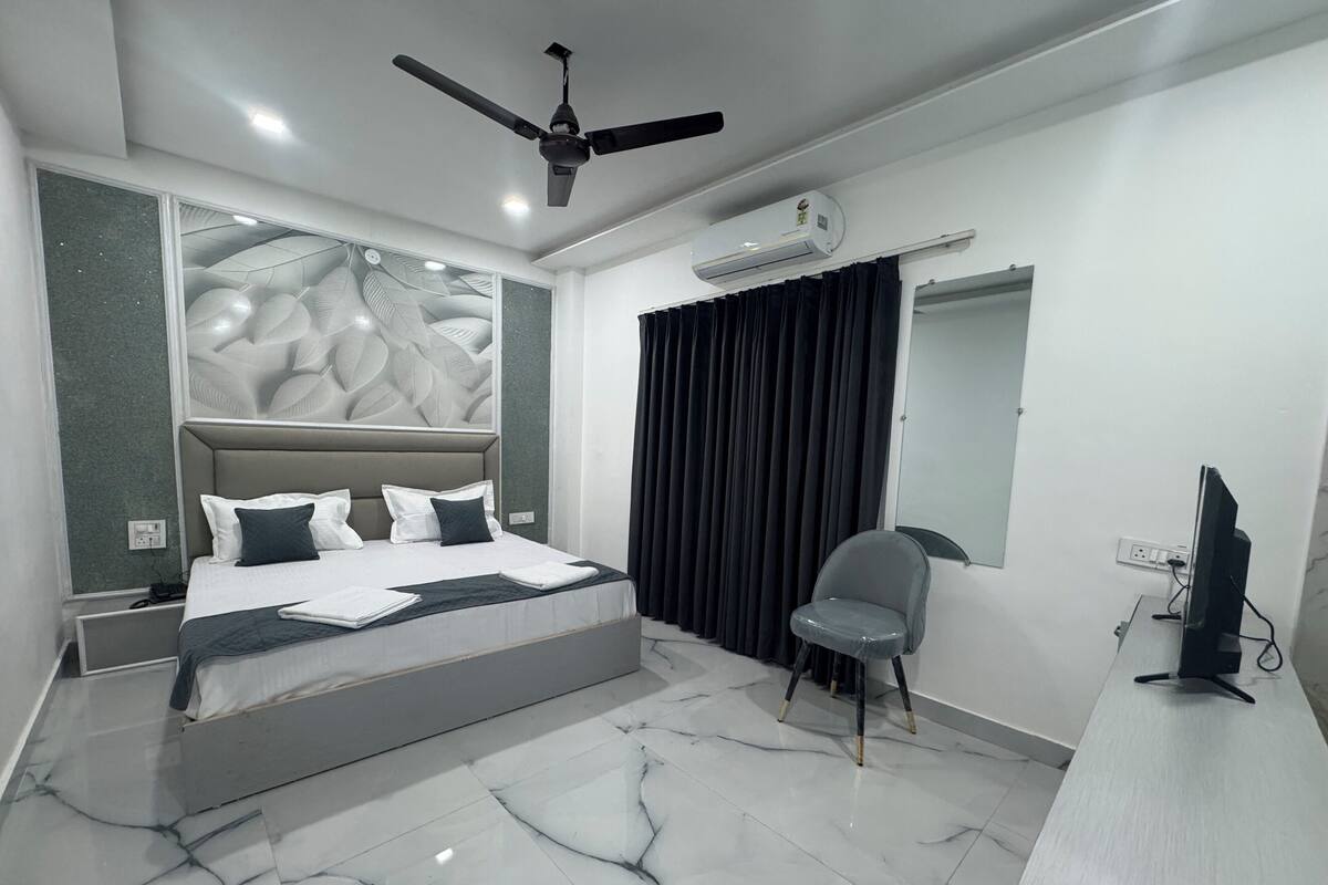 Une chambre moderne avec un lit, une chaise, un bureau et un ventilateur de plafond.