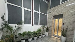 A lobby with a marble floor, multiple potted plants, and a glass door entrance. - Urban Hive By T And M Hotels (Haridwar)