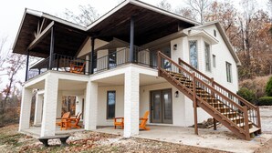 A two-story house with a covered porch, a staircase, and outdoor seating. - Remodeled Lakefront Retreat with Hot Tub (Lyon County)