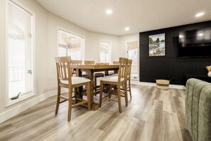 Un coin repas avec une table et des chaises en bois, un téléviseur fixé au mur et un tableau représentant le lac Barkley.