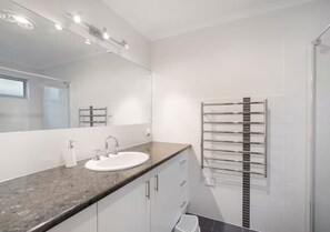Ein modernes Badezimmer mit einem weißen Waschbecken, einem Spiegel und einem Handtuchhalter.