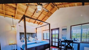 Ein Schlafzimmer mit einem Himmelbett, einem Schreibtisch mit Stühlen und großen Fenstern.