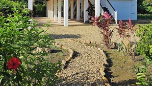 Ein zweistöckiges Haus mit Balkon, überdachter Veranda und kleinem Anbau für eine Garage.