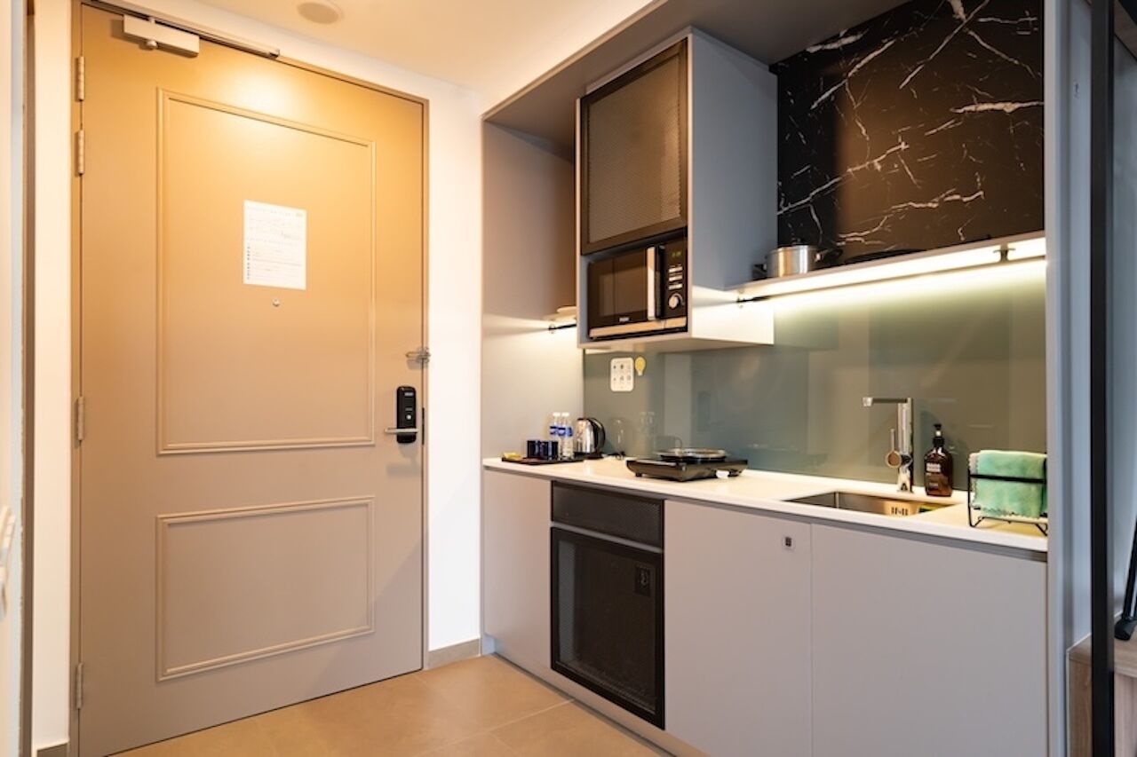 Een kleine keuken met een magnetron, fornuis en wasbak.