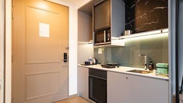 Een kleine keuken met een magnetron, fornuis en wasbak.