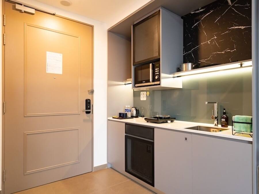 Een kleine keuken met een magnetron, fornuis en wasbak.