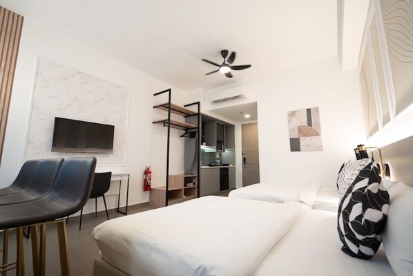 A modern hotel room with a bed, a desk, a chair, a TV, and a ceiling fan.