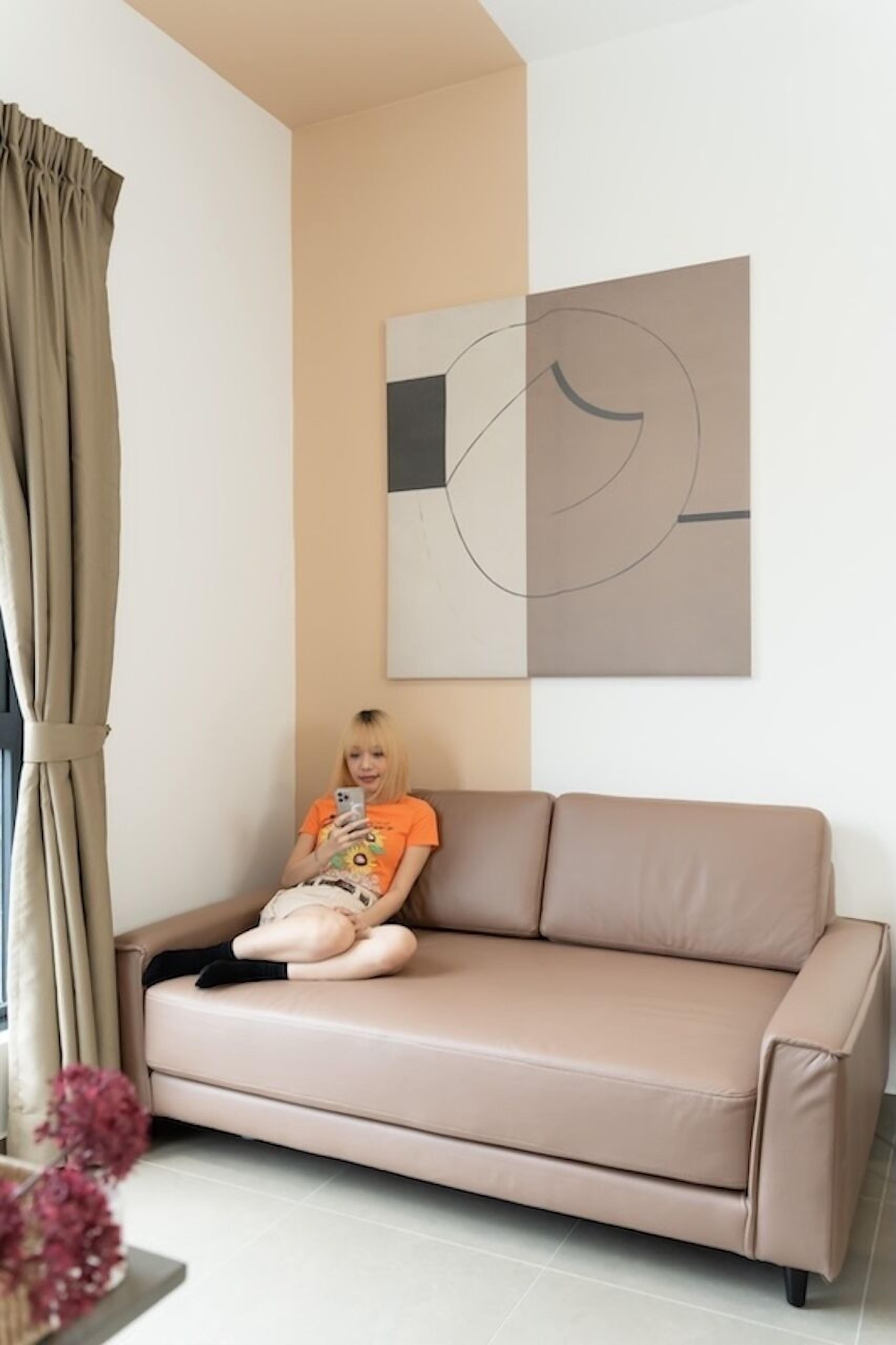 A beige sofa in a room with a large abstract painting on the wall.
