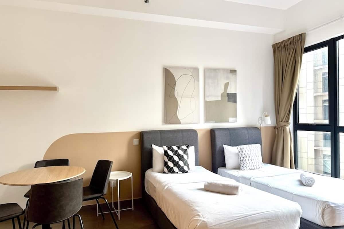 A hotel room with two beds, a round table, and a small chair.