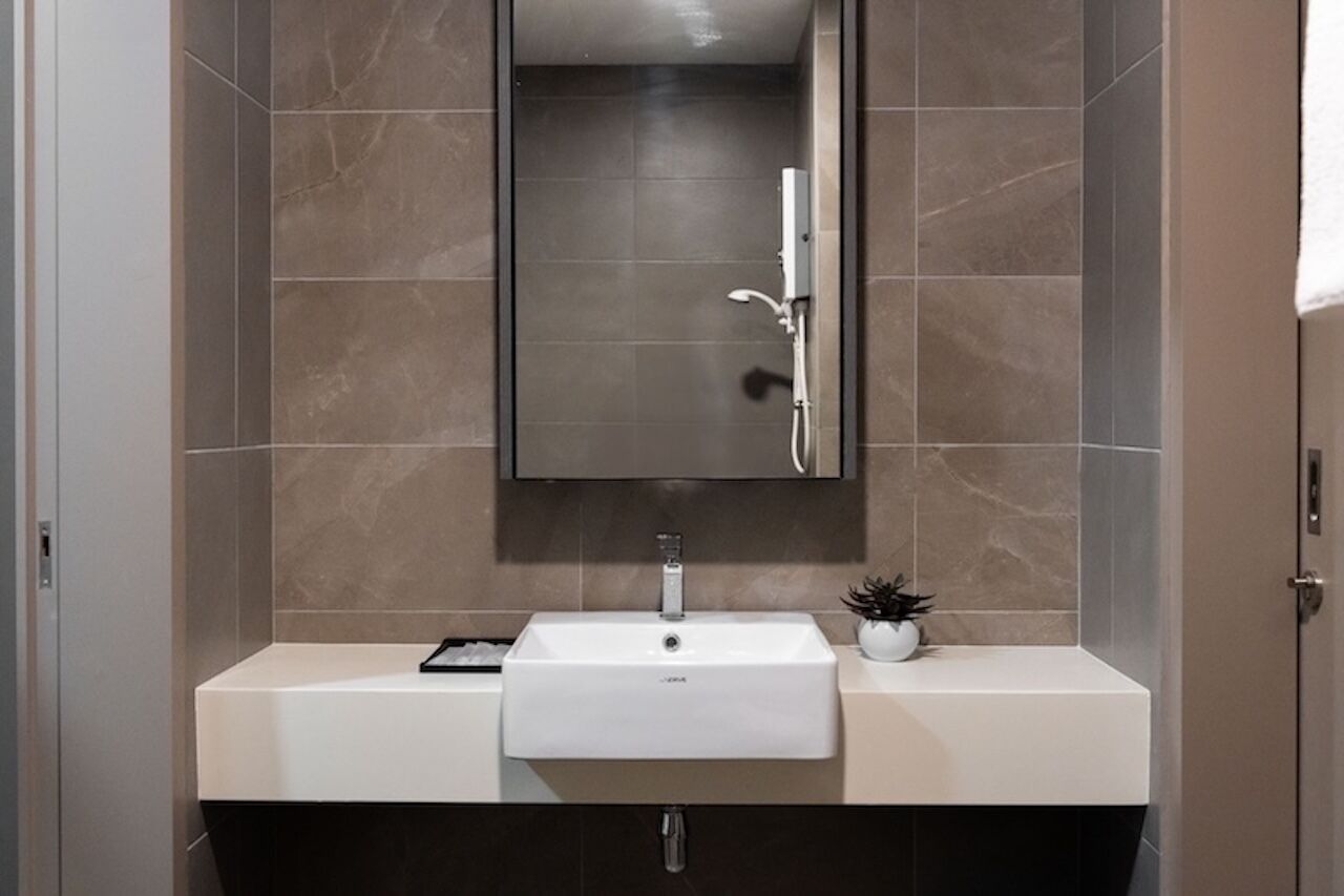 A modern bathroom with a white sink, a mirror, and a shower.