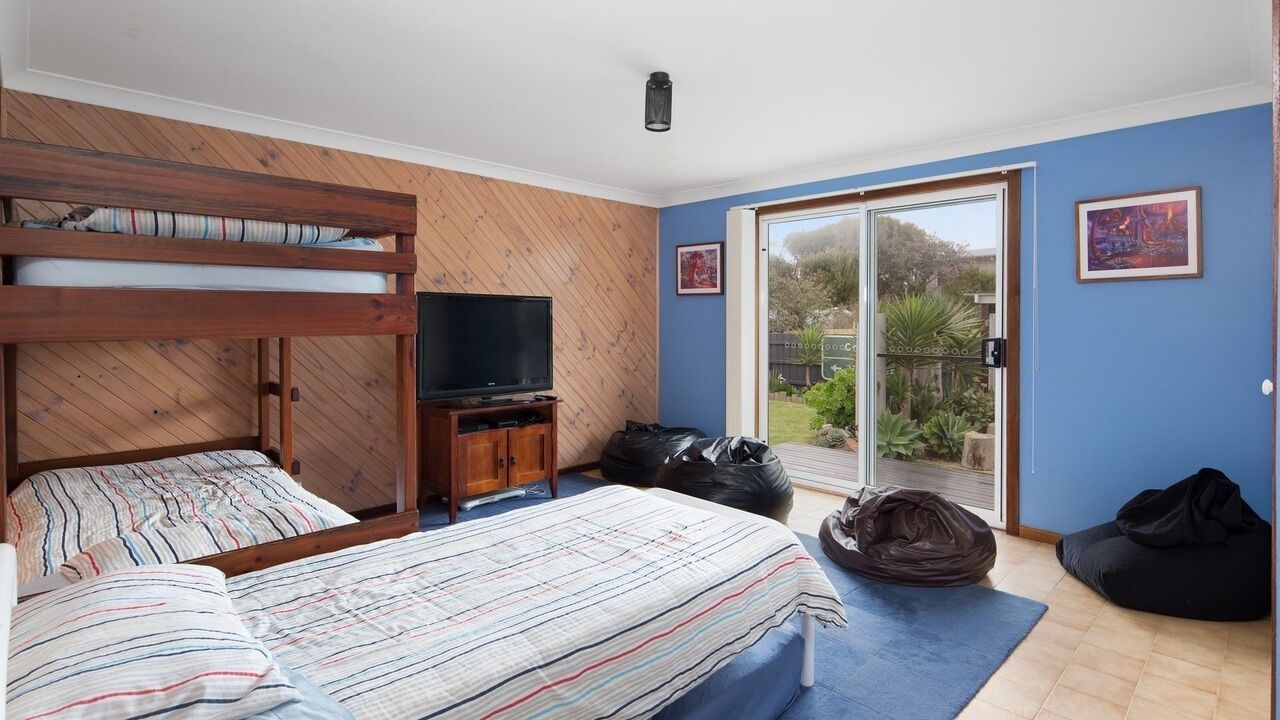 A room with bunk beds, a television, a sliding glass door to a garden, and a black bean bag.