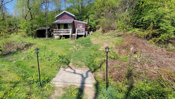 A wooden cabin with a porch, surrounded by greenery and a path leading to it. - Cute 1-bedroom off grid cabin in Winfield for a cozy getaway (Winfield)