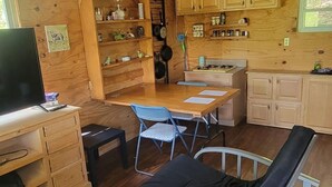 A wooden cabin with a loft bedroom, a dining area, and a kitchen. - Cute 1-bedroom off grid cabin in Winfield for a cozy getaway (Winfield)