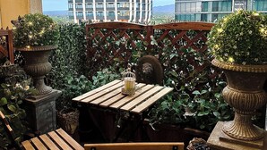 Ein Sitzbereich im Freien mit Holztisch und Bänken, umgeben von Grünpflanzen und Zierteichen.