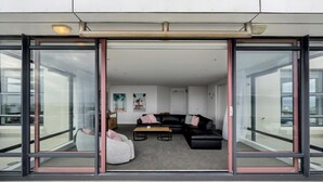 Un interior moderno con un sofá de cuero negro, un sillón blanco y una mesita.