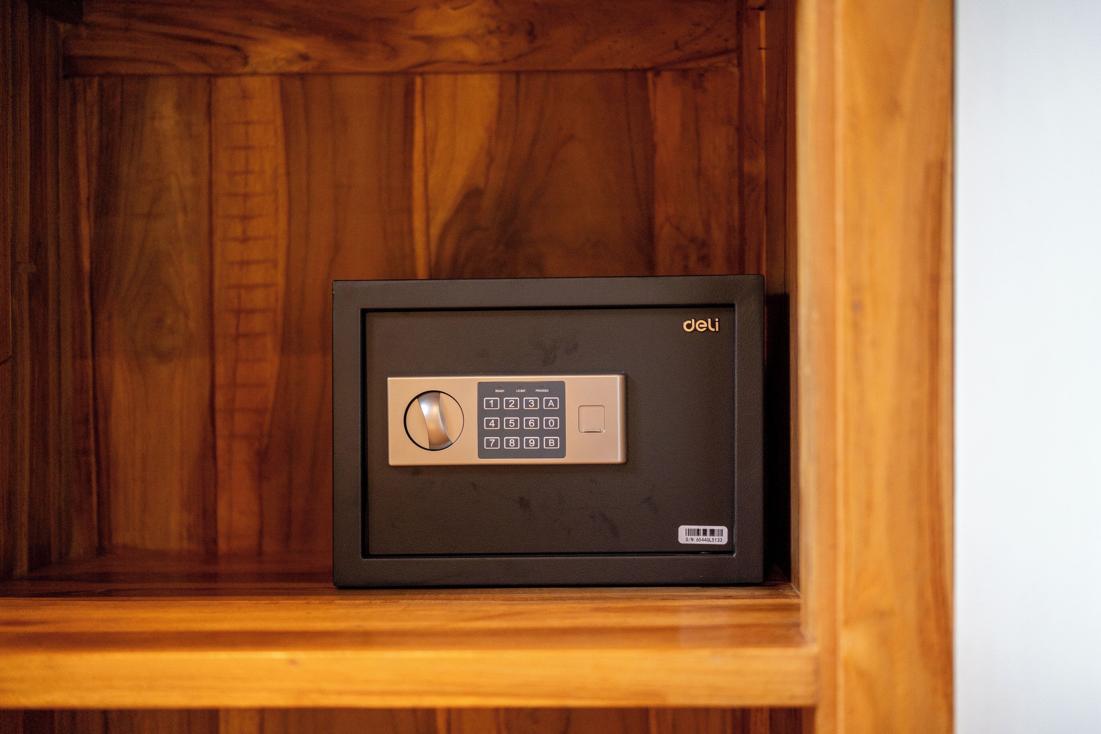 A safe with a keypad and a barcode on the bottom right, placed in a wooden cabinet.