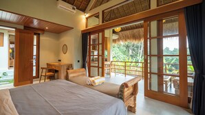 Un dormitorio con una cama grande, muebles de madera y un balcón con vistas a zonas verdes.