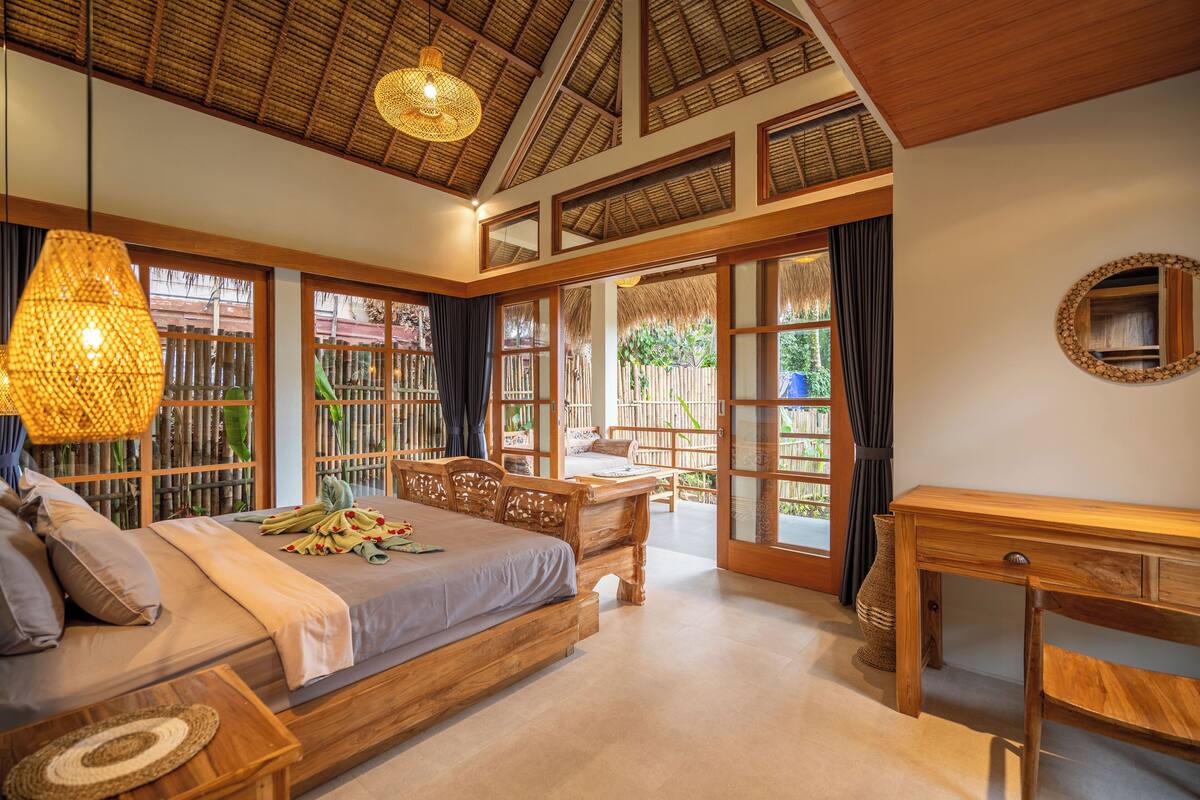 A bedroom with a large bed, wooden furniture, and a view of the outdoors.
