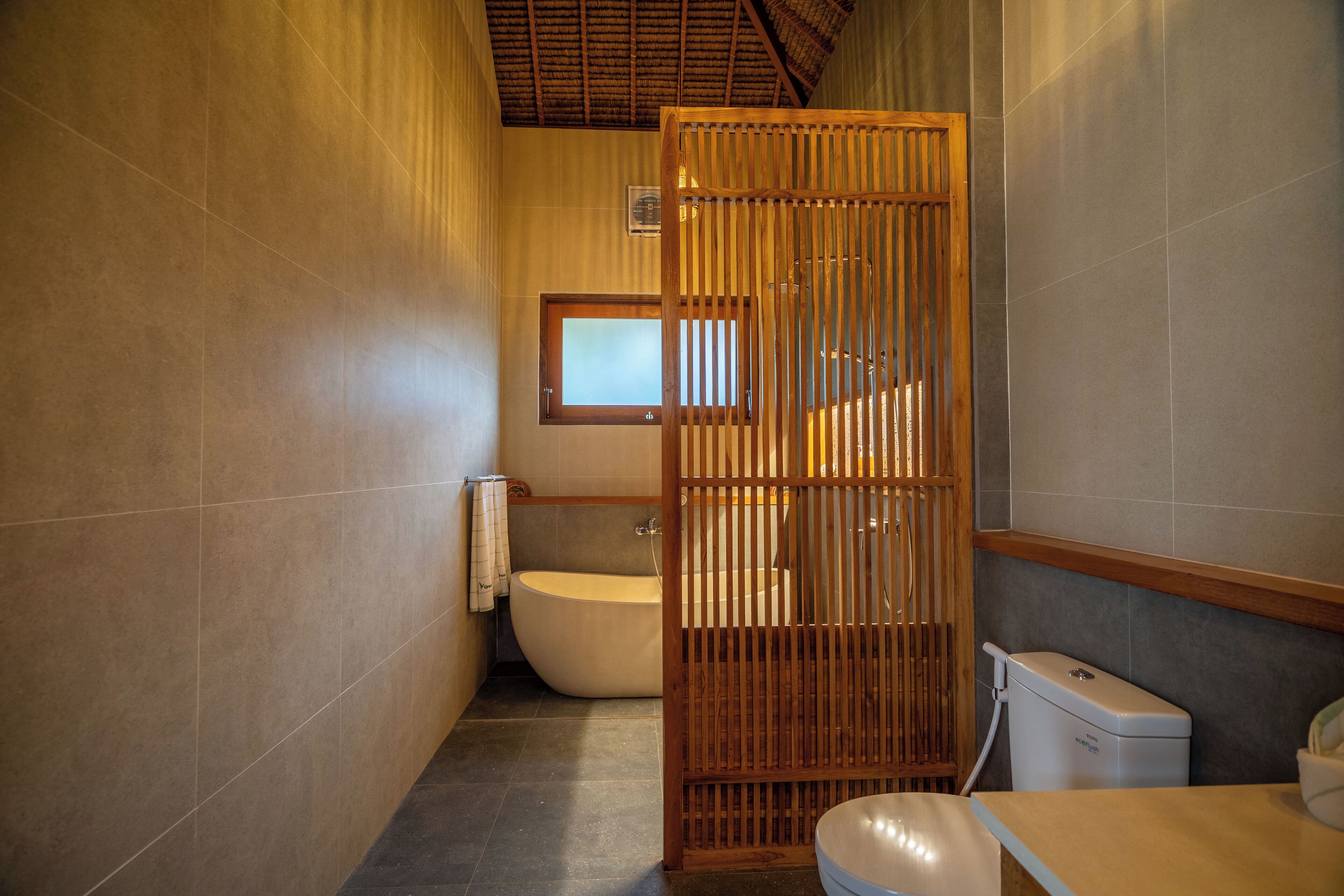 Une salle de bain avec une baignoire, des toilettes et une cloison en bois.