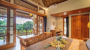 Un dormitorio espacioso con una cama grande, un escritorio de madera y un balcón con vistas a zonas verdes.