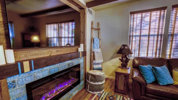 A cozy living room with a fireplace, a leather sofa, and a patterned rug.