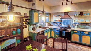 A kitchen with wooden cabinets, a dining table, and hanging lights.