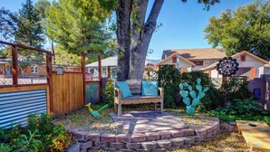 A patio area with a wooden bench, a cactus sculpture, and a wooden fence.