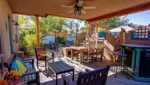 An outdoor patio with wooden furniture, a ceiling fan, and a view of the surrounding area.