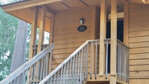 A wooden cabin with a balcony, a metal railing, and a number '29' sign.