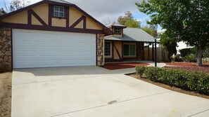 A two-story house with a stone facade, a large garage, and a covered porch. - 3-bedroom house in lovely Wildomar with cool AC (Wildomar)