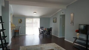 Un salon spacieux comprenant un coin repas, un escalier et un téléviseur posé sur un meuble.
