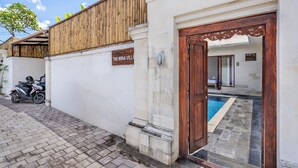 A villa with a wooden fence, a sign reading "The Wina Villa," a swimming pool, and a scooter parked outside. - The Wina Ambengan Canggu (Canggu)