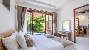 A bedroom with a bed, a desk, and a view of a garden and pool. - The Wina Ambengan Canggu (Canggu)