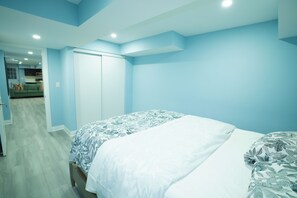 A bedroom with a bed, a wardrobe, and a view into the kitchen.
