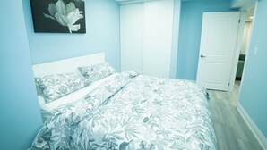 Una camera da letto con copriletto floreale, una testiera bianca e una porta che dà su un'altra stanza.