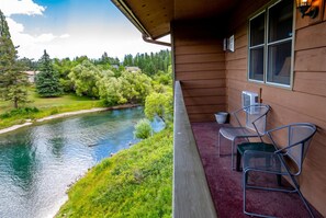 A wooden building with a balcony overlooking a river and greenery.