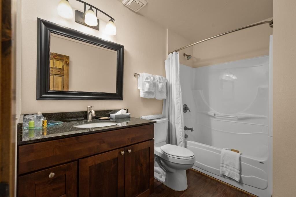 A bathroom with a dark wood vanity, a white sink, a large mirror, and a shower with a glass door.