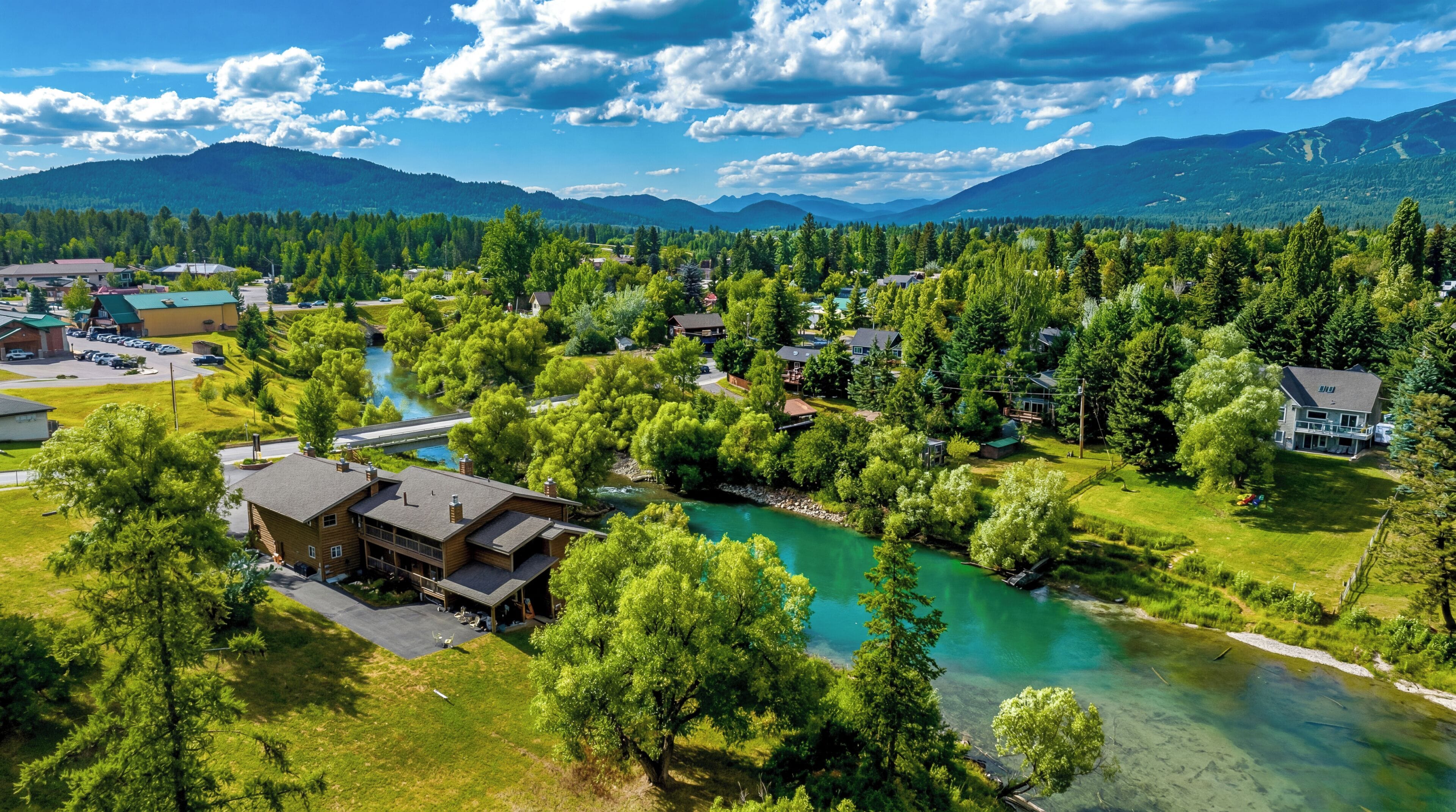 A residential area with houses, a river, and mountains in the background.