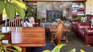 A cozy interior with a stone fireplace, wooden furniture, and various plants. - Duck Inn Lodge (Whitefish)