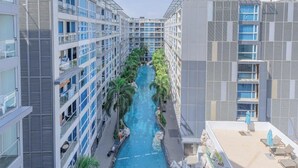 Un hôtel moderne doté d’une piscine centrale, bordée de gratte-ciel, offrant une vue sur la piscine et la végétation environnante.