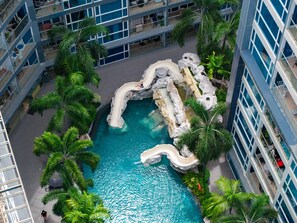 Una piscina interior con tobogán, rodeada de palmeras y arquitectura moderna.