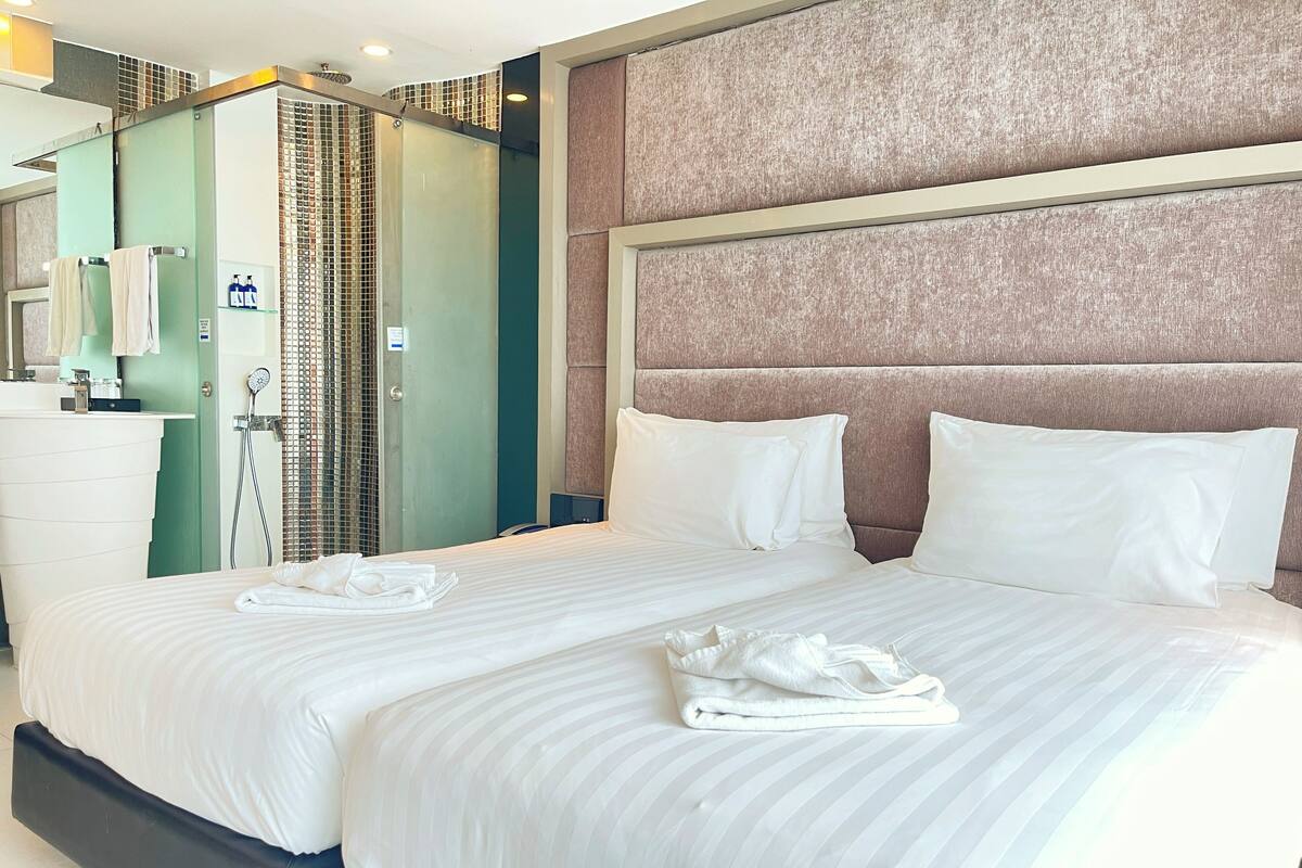 Une chambre d’hôtel avec deux lits, une salle de bain avec douche et un mini-bar.