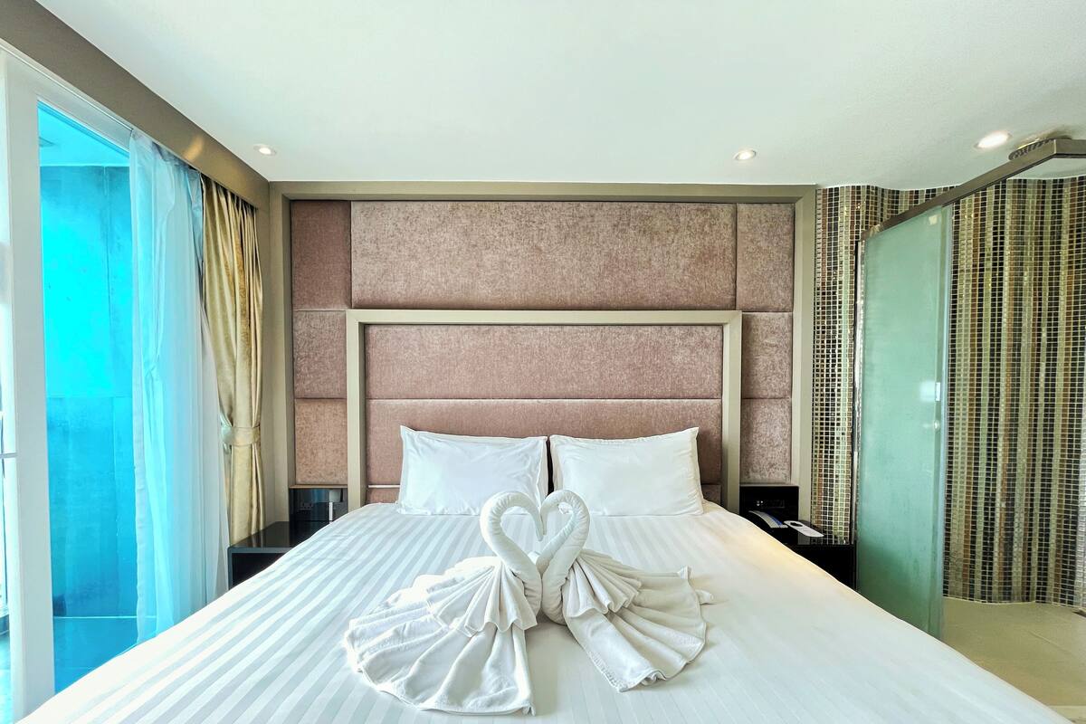Une chambre d’hôtel avec un grand lit, une tête de lit et une table de chevet.