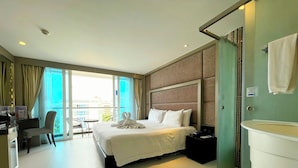Une chambre d’hôtel avec un grand lit, un bureau avec une chaise, une salle de bain et une vue sur la ville par la fenêtre.
