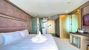 Une chambre d’hôtel avec un grand lit, une salle de bain, une télévision et un minibar.