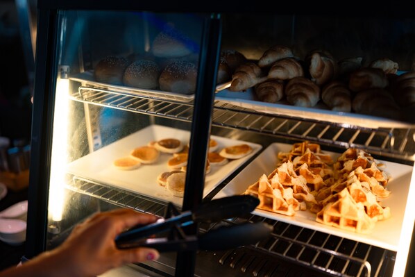 An oven with trays of baked goods, including buns and waffles. - Vanko International Hotel Pattaya (Pattaya)