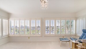 A spacious room with large windows, a blue chair, and a decorative table. - Spacious Condo with Stunning View (Oakland)