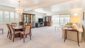 A spacious living area with a dining table, chairs, a sofa, and a TV. - Spacious Condo with Stunning View (Oakland)