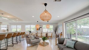 A modern kitchen with a dining area, large windows, and a cozy seating area with a sofa and chairs. - Private Palm Beach Pool Home Putting Green near BEACH Restaurants (North Palm Beach)